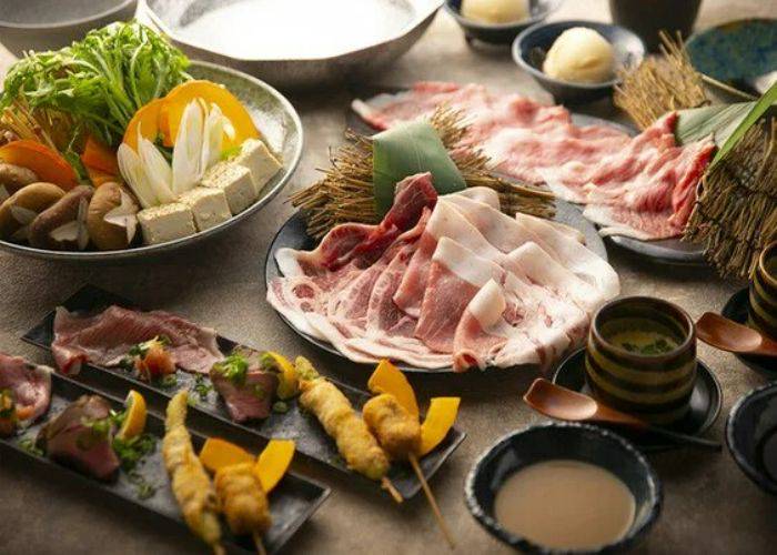 A platter of different dishes at Sukiyaki Kushikatsu Haruna Honcho in Osaka, including hot pot, sukiyaki, and skewers.